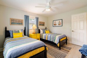 A bedroom with two beds, a ceiling fan, and a door. - Modern Coastal Pool Retreat • Private Heated Pool • Minutes to Siesta Key Beach (Sarasota)