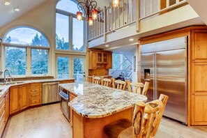 A spacious kitchen with a large island, wooden cabinets, and a stainless steel refrigerator.