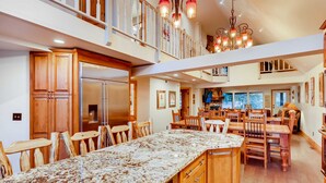 A spacious kitchen with a large island, wooden cabinets, and a dining area with multiple chairs. - Breck Town Lodge | In Town | Walkability (Breckenridge)