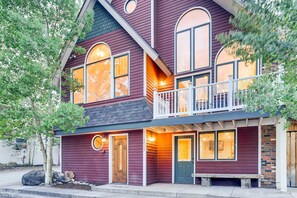 A two-story house with a balcony, large windows, and a front door.