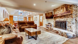 A spacious living area with a stone fireplace, leather sofas, and a wooden coffee table. - Breck Town Lodge | In Town | Walkability (Breckenridge)