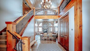 A spacious hallway with a wooden staircase, a dining area with a fireplace, and a view of the upper level. - Castle Butenham by Cottonwood Lodging (Brighton)