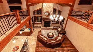A spacious loft-style living area with a stone fireplace, leather sofa, and a dining table with chairs. - Castle Butenham by Cottonwood Lodging (Brighton)