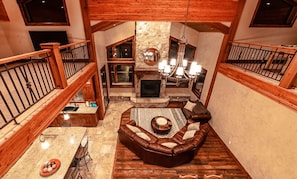 A spacious loft-style living area with a stone fireplace, leather sofa, and a dining table with chairs.