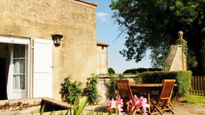 A rustic building with a door, a window, and a small table with chairs outside.