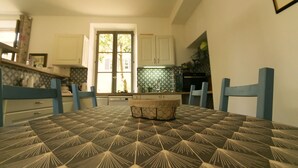 A dining table with a patterned tablecloth, blue chairs, and a central decorative item.