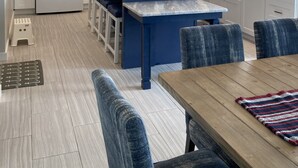 A modern kitchen with white cabinets, a blue island, and a dining area with blue chairs.