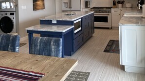 A modern kitchen with white cabinets, a central island, and built-in appliances.