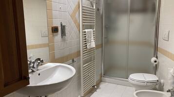 A bathroom with a sink, toilet, and glass shower enclosure.