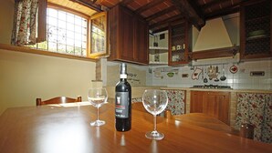 Een houten eettafel met twee wijnglazen en een fles wijn.