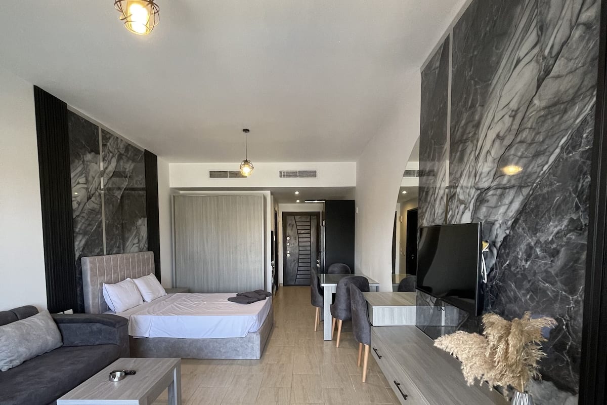 Un salon moderne avec un canapé, un lit, un téléviseur et un mur en marbre.