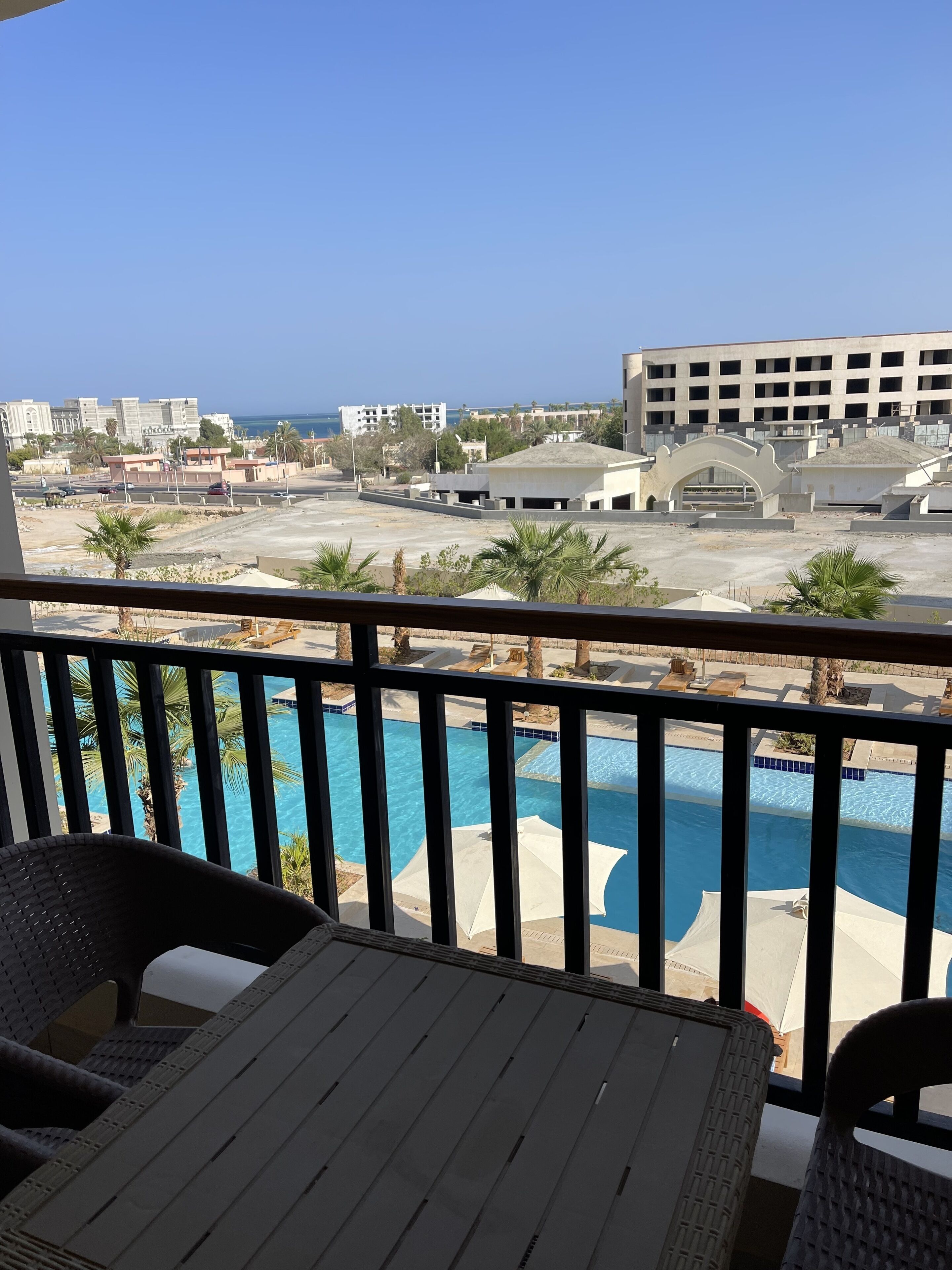 A balcony with wicker furniture overlooking a swimming pool and a view of the cityscape.