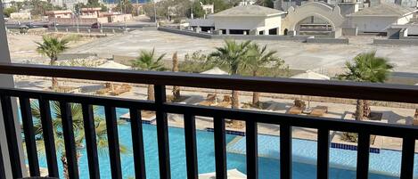 A balcony with wicker furniture overlooking a swimming pool and a view of the cityscape.