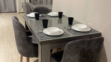A dining table with four chairs, a flat-screen TV, and a curtain in the background.