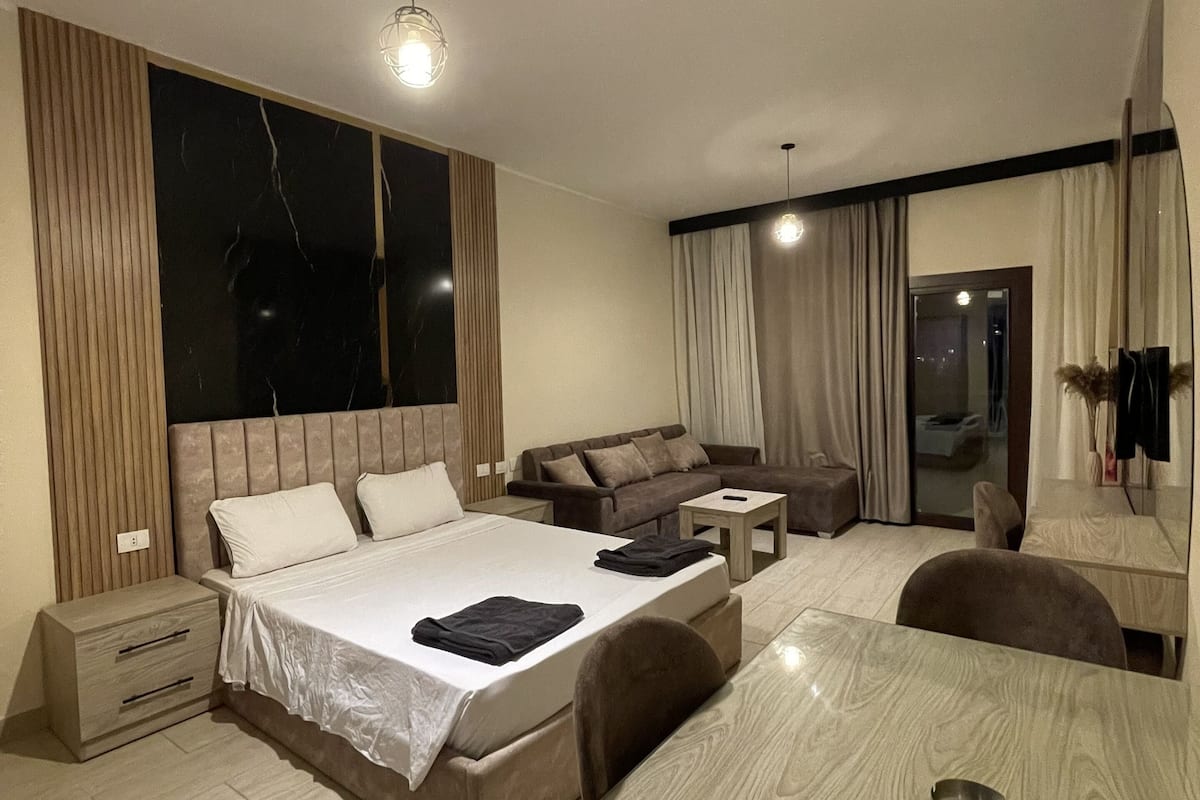 Une chambre d’hôtel moderne avec un grand lit, un canapé, une table à manger et un miroir.