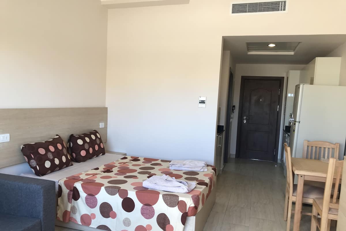Une chambre d’hôtel avec un lit, un bureau et une chaise. Une porte donne accès à une autre pièce.