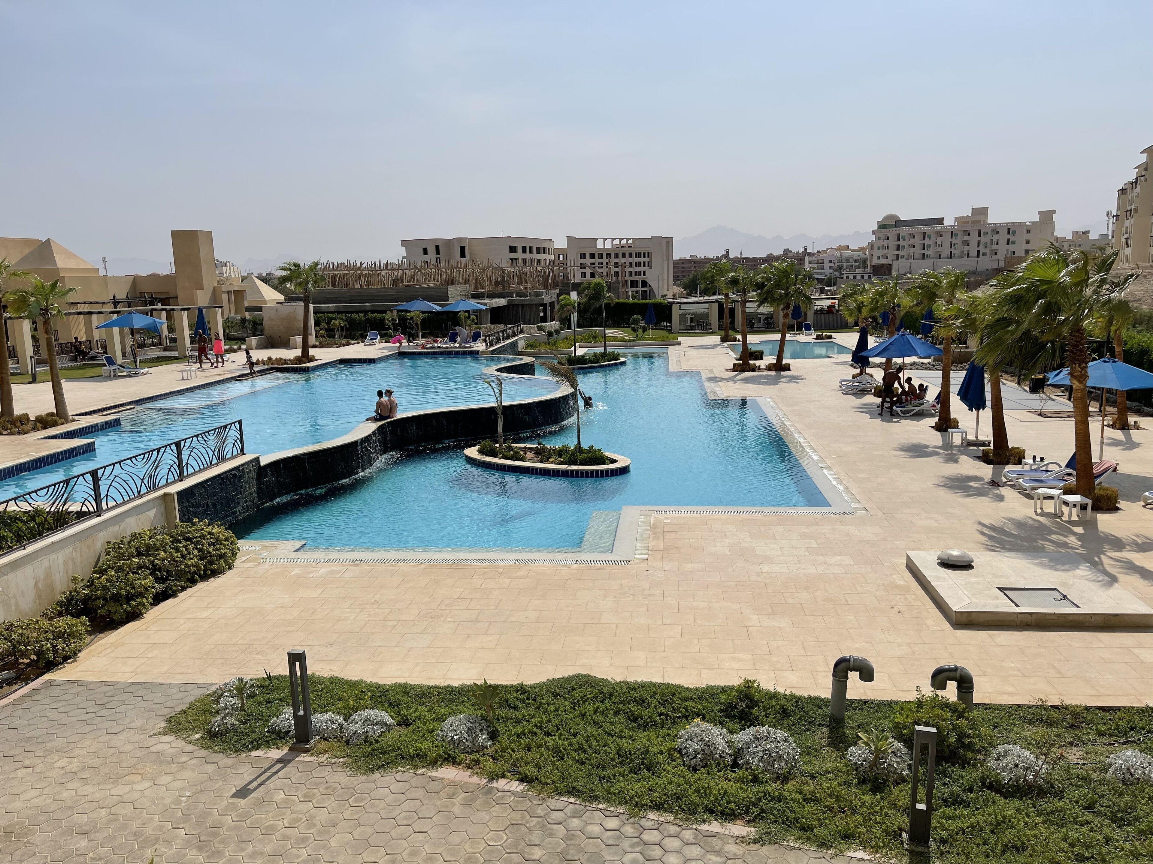 A swimming pool with a curved design, surrounded by lounge chairs and umbrellas.