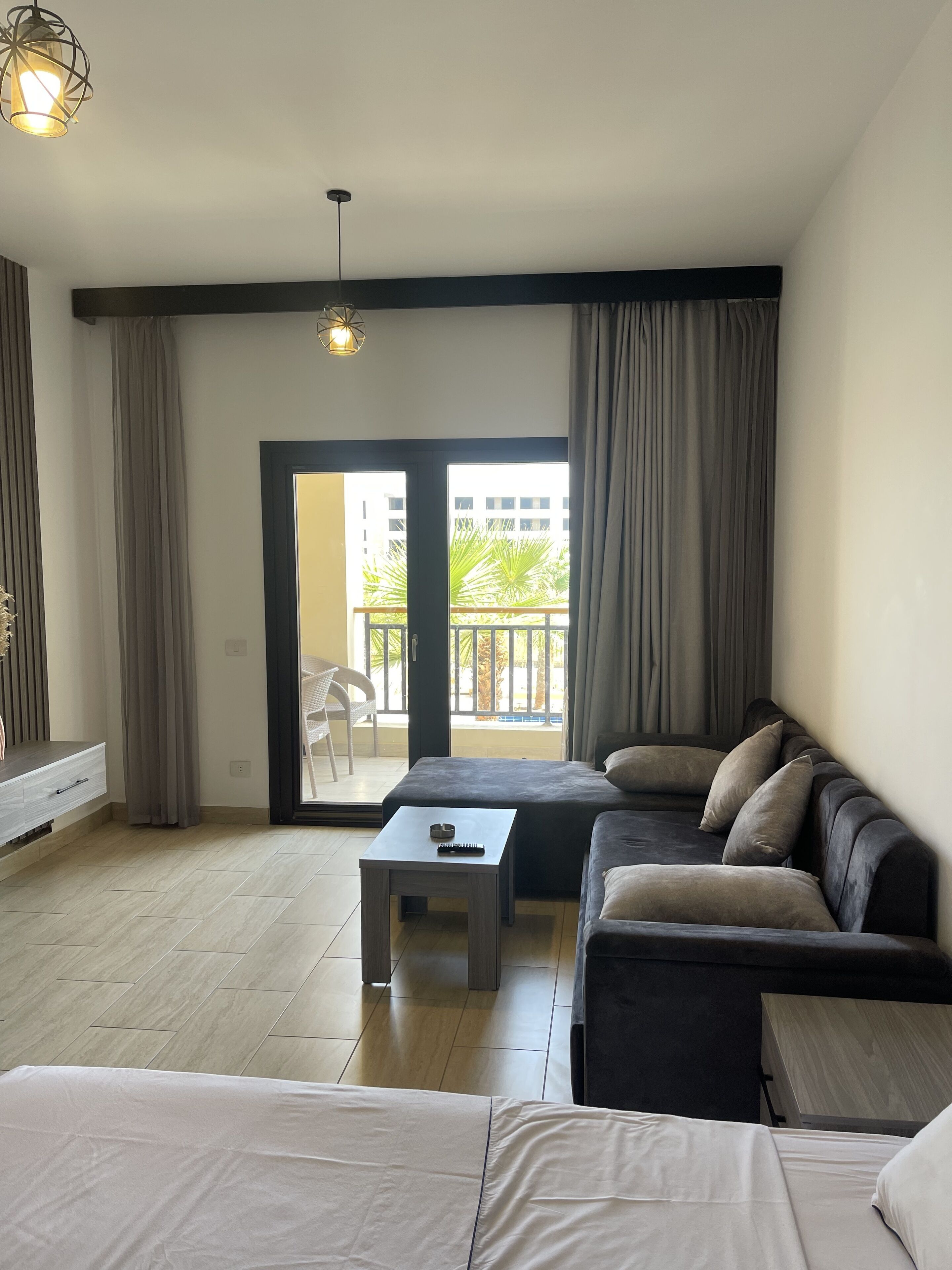 En moderne stue med sofa, sofabord og udsigt til en balkon med udendørs møbler.