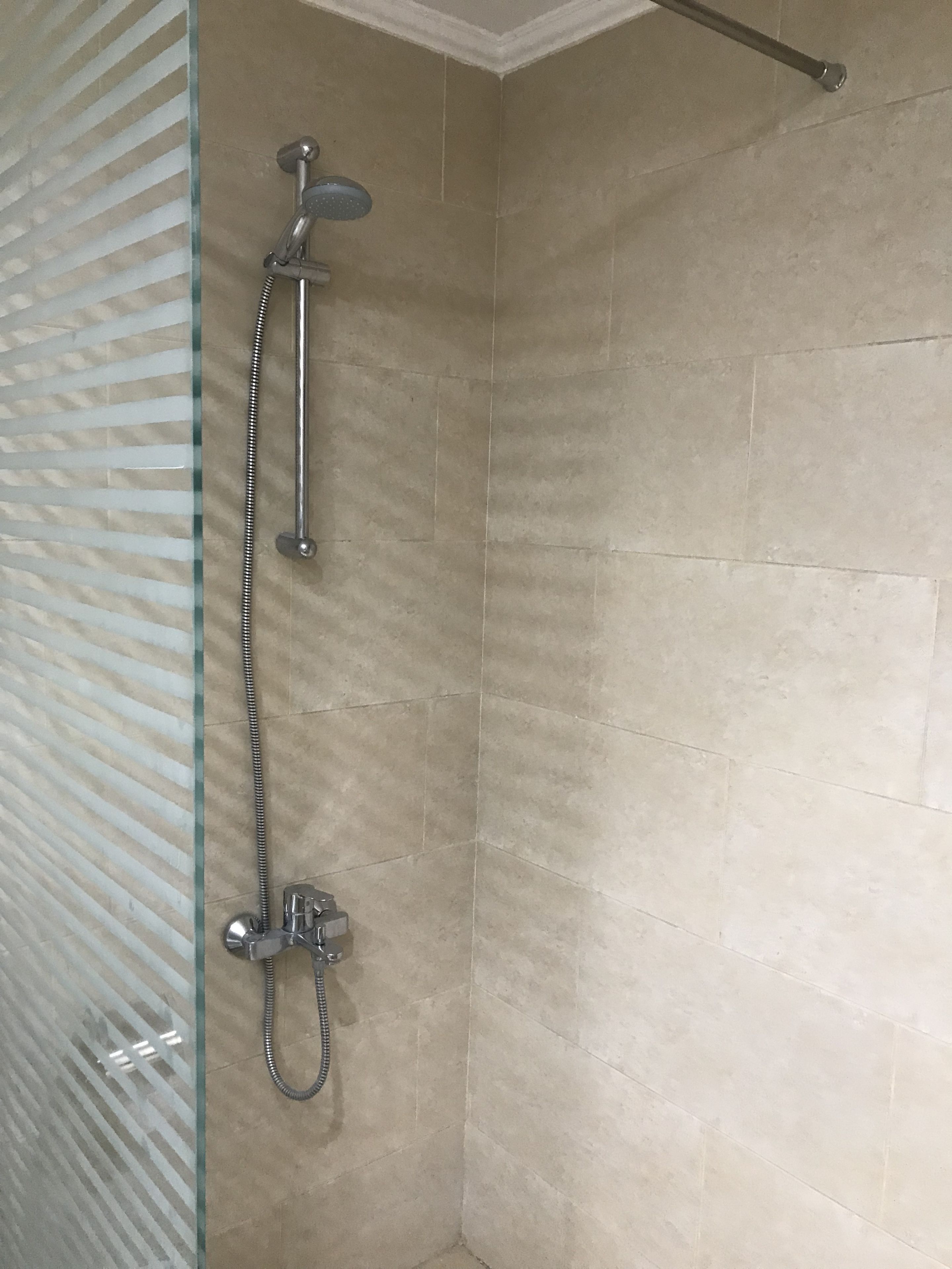 A shower with a glass door and a metal showerhead.