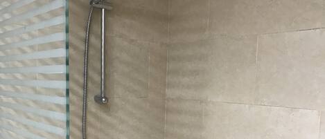 A shower with a glass door and a metal showerhead.