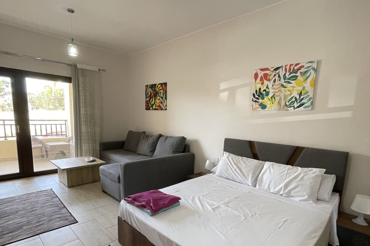 Une chambre à coucher moderne, dotée d’un grand lit, d’un canapé, d’une table basse et d’œuvres d’art accrochées aux murs.