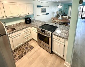 A kitchen with white cabinets, a granite countertop, a built-in oven, and a coffee maker. - 🦩 Charming 2BR Condo Pool View ~ Siesta Key Bay Oaks🦩 (Sarasota)