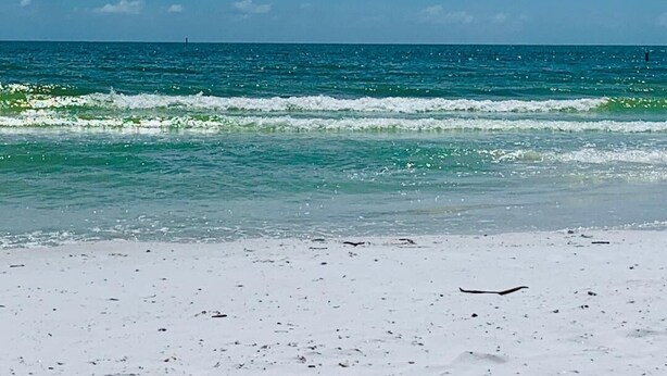 Een strand met helderblauw water en een zandstrand.