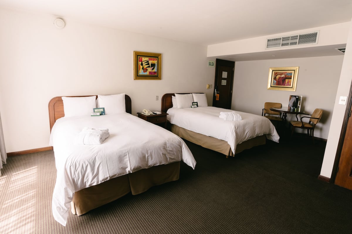 Una habitación de hotel con dos camas, un escritorio, una silla y una puerta.