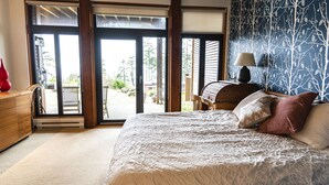 Una camera da letto con un letto, una cassettiera in legno e vista all'esterno tramite una porta scorrevole in vetro.