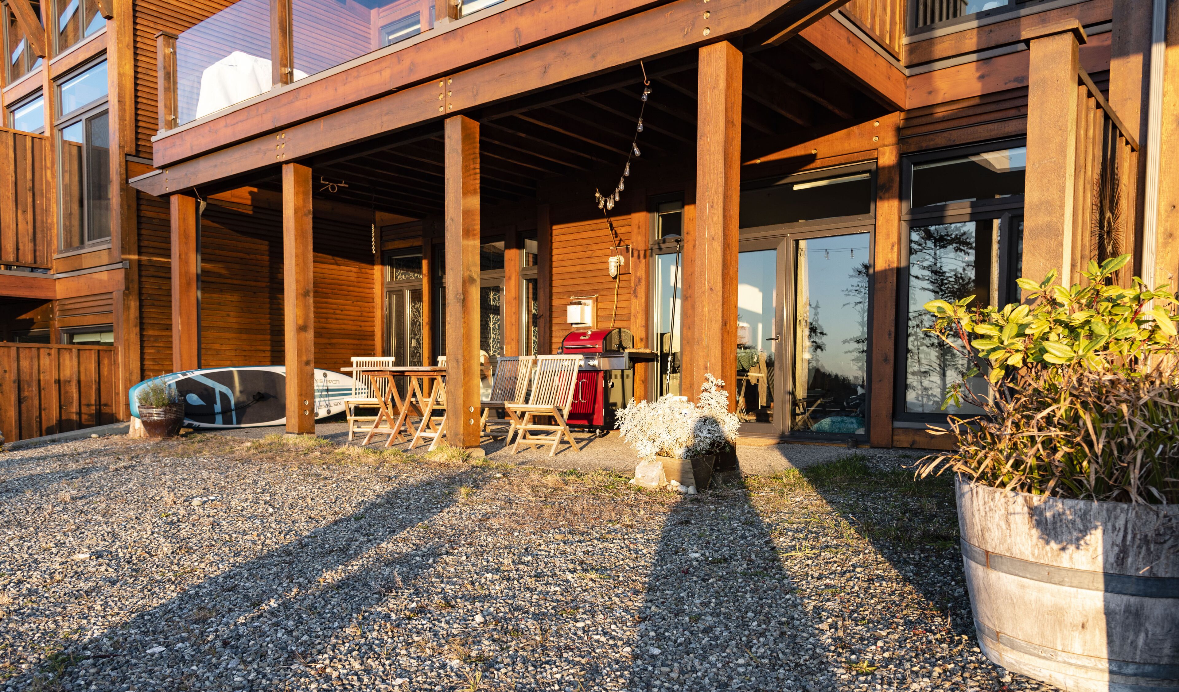 A wooden building with a covered patio, outdoor seating, and a barbecue grill.