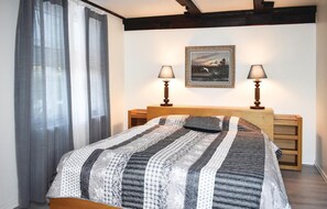 A bedroom with a bed, two bedside lamps, a framed picture on the wall, and a window with curtains. - Lovely home in Klippan with sauna (Klippan)