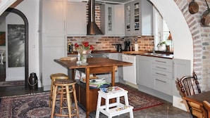 A kitchen with a central island, white cabinets, a brick wall, and a hanging pot rack. - Lovely home in Klippan with sauna (Klippan)
