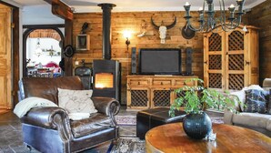 A cozy living room with a fireplace, leather armchair, and wooden walls. - Lovely home in Klippan with sauna (Klippan)