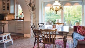 A spacious kitchen with a large window, a dining area with a chandelier, and a cozy seating area with a view of the outdoors. - Lovely home in Klippan with sauna (Klippan)