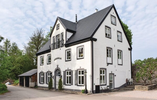 A two-story building with a white facade and dark roof, featuring multiple windows and a central entrance with a decorative arch. - Lovely home in Klippan with sauna (Klippan)
