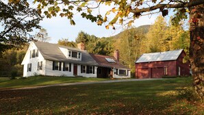 A two-story house with a large front porch and a separate red barn. - Vermont Farmhouse in the Heart of the Green Mountains (Granville)