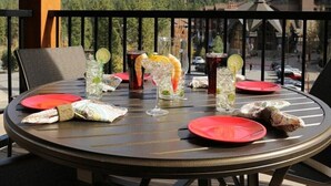 Une table ronde avec des assiettes rouges, des verres remplis de boissons et, en arrière-plan, une vue sur une montagne boisée.
