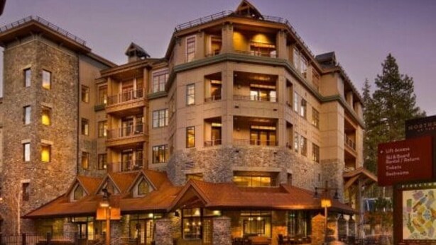 A multi-story hotel with stone exterior and multiple balconies, featuring a signboard with amenities. - Welk Resorts- 2 BD NORTH VILLAGE #1 (Truckee)