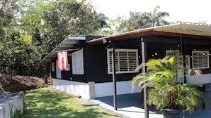 A black and white building with a covered porch, a potted plant, and a flag.