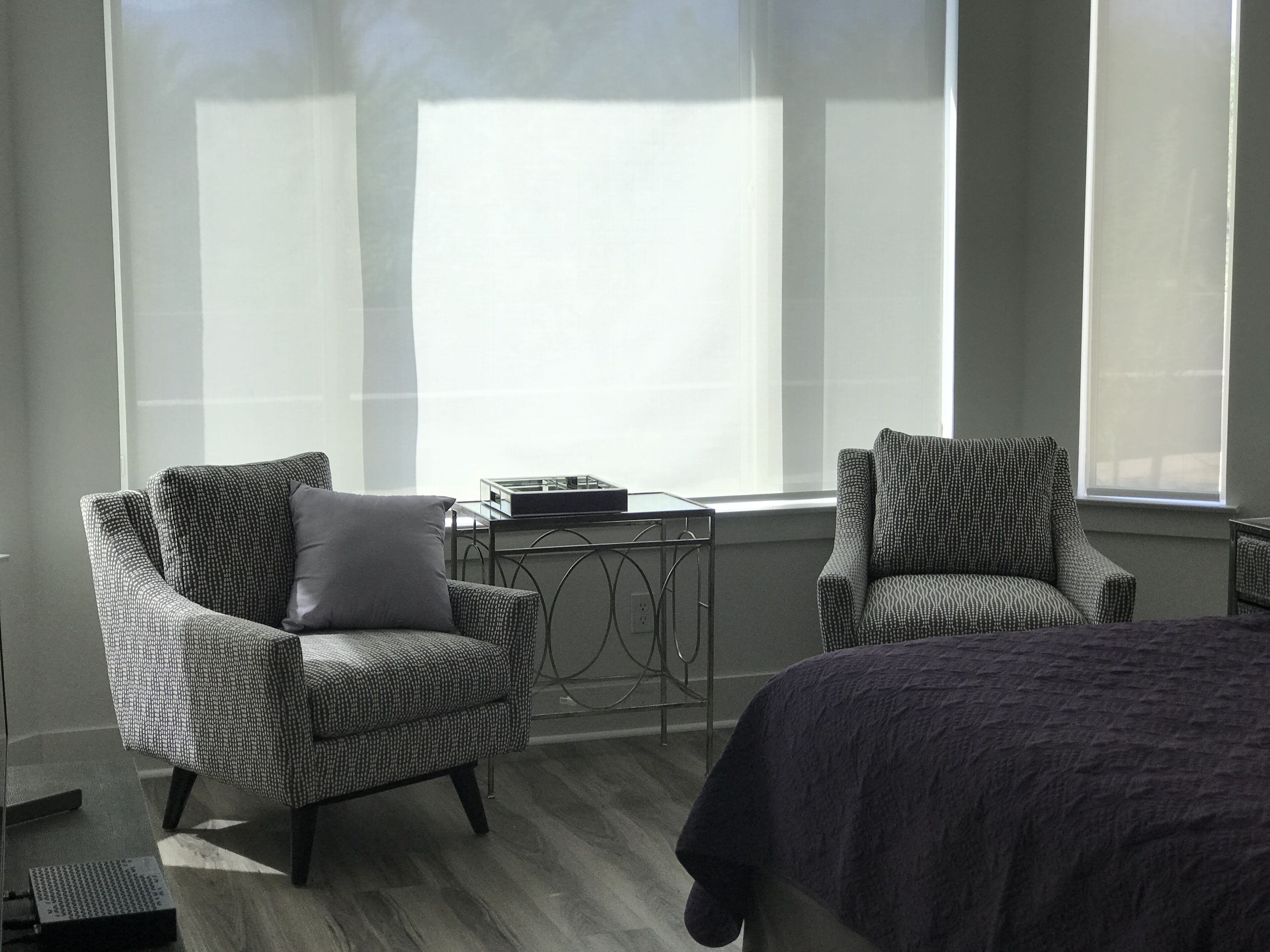 A room with two armchairs, a small table, and a bed.