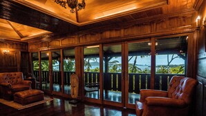 A spacious room with large windows, wooden flooring, and leather armchairs. - Rohotu Fare (Bora Bora)