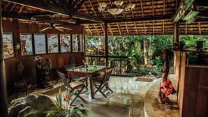A wooden dining area with a table and chairs, a ceiling fan, and a view of the outdoors. - Rohotu Fare (Bora Bora)