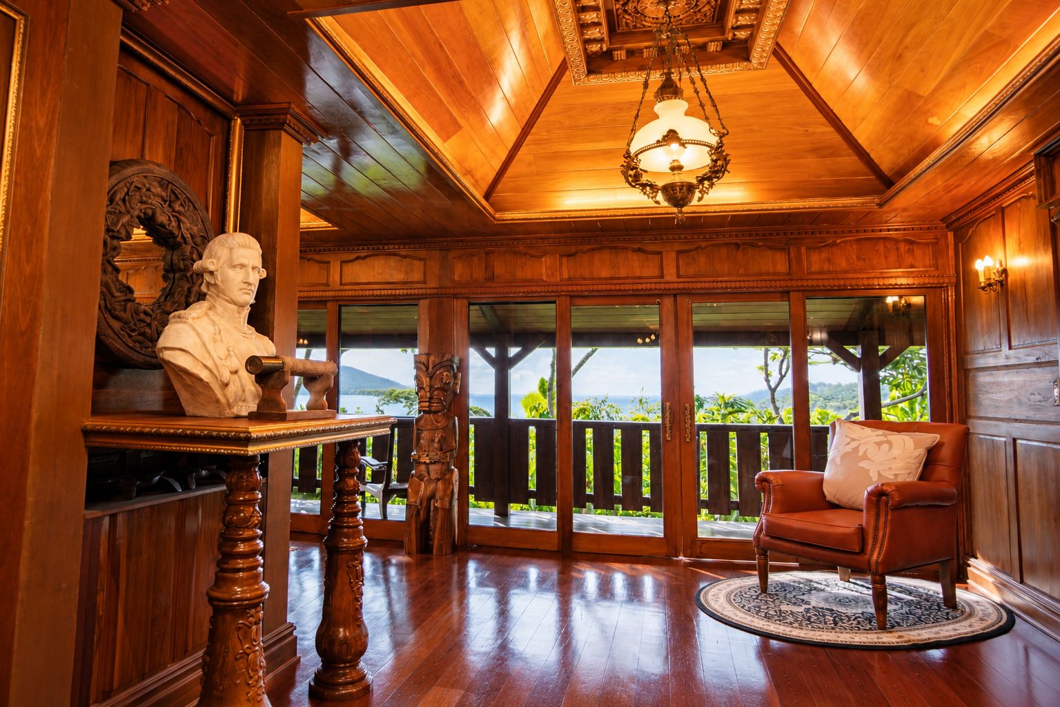 A room with a wooden ceiling, a chandelier, a bust on a table, a sofa, and a view of the outdoors.