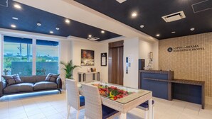 A reception area with a reception desk, a sofa, a dining table with chairs, and a large window with a view.