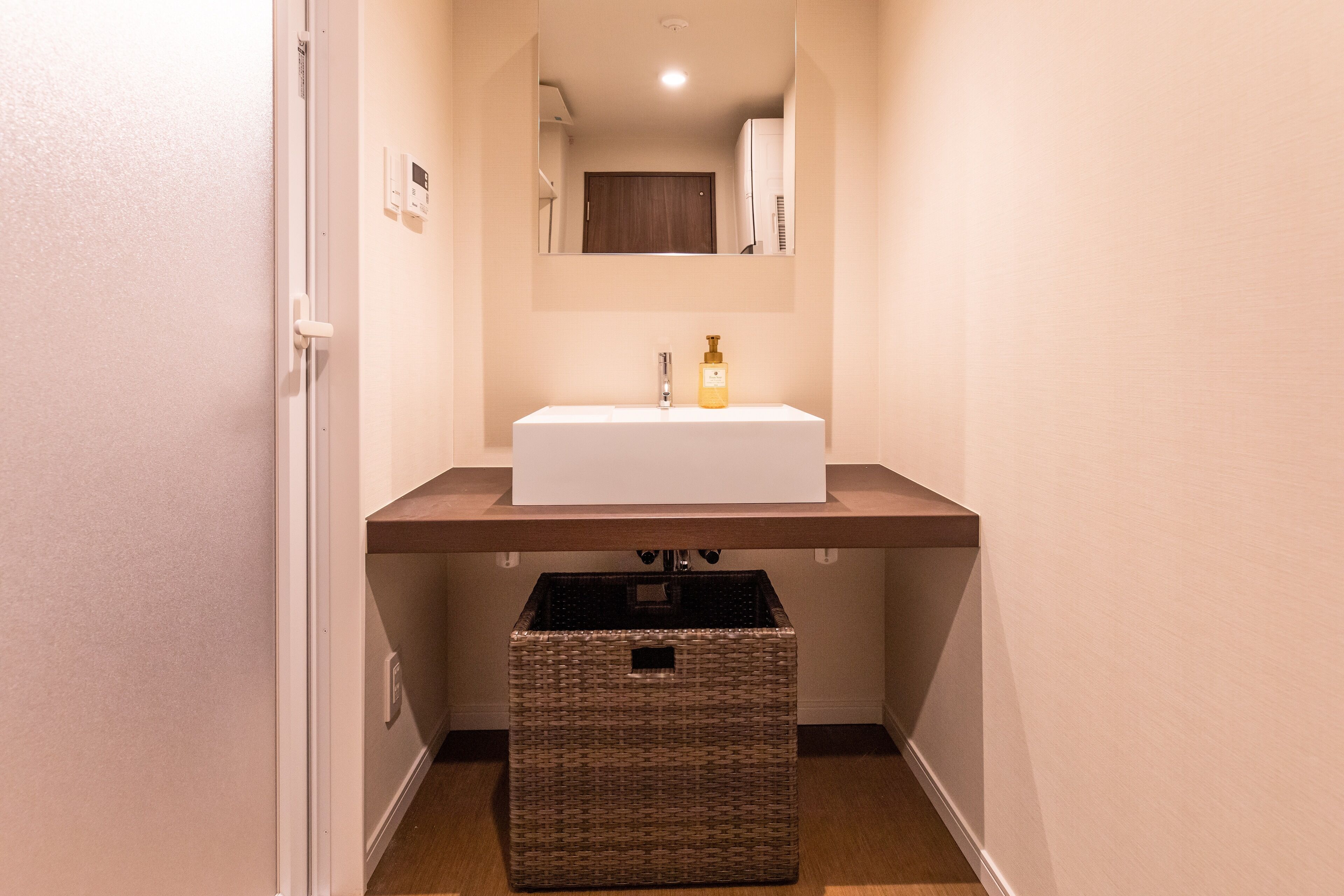 A bathroom with a white sink, a mirror above it, and a wicker basket below.