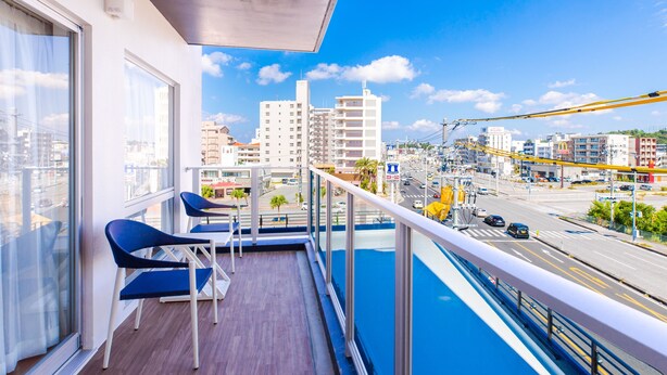 A balcony with a view of a cityscape, including buildings and a road.