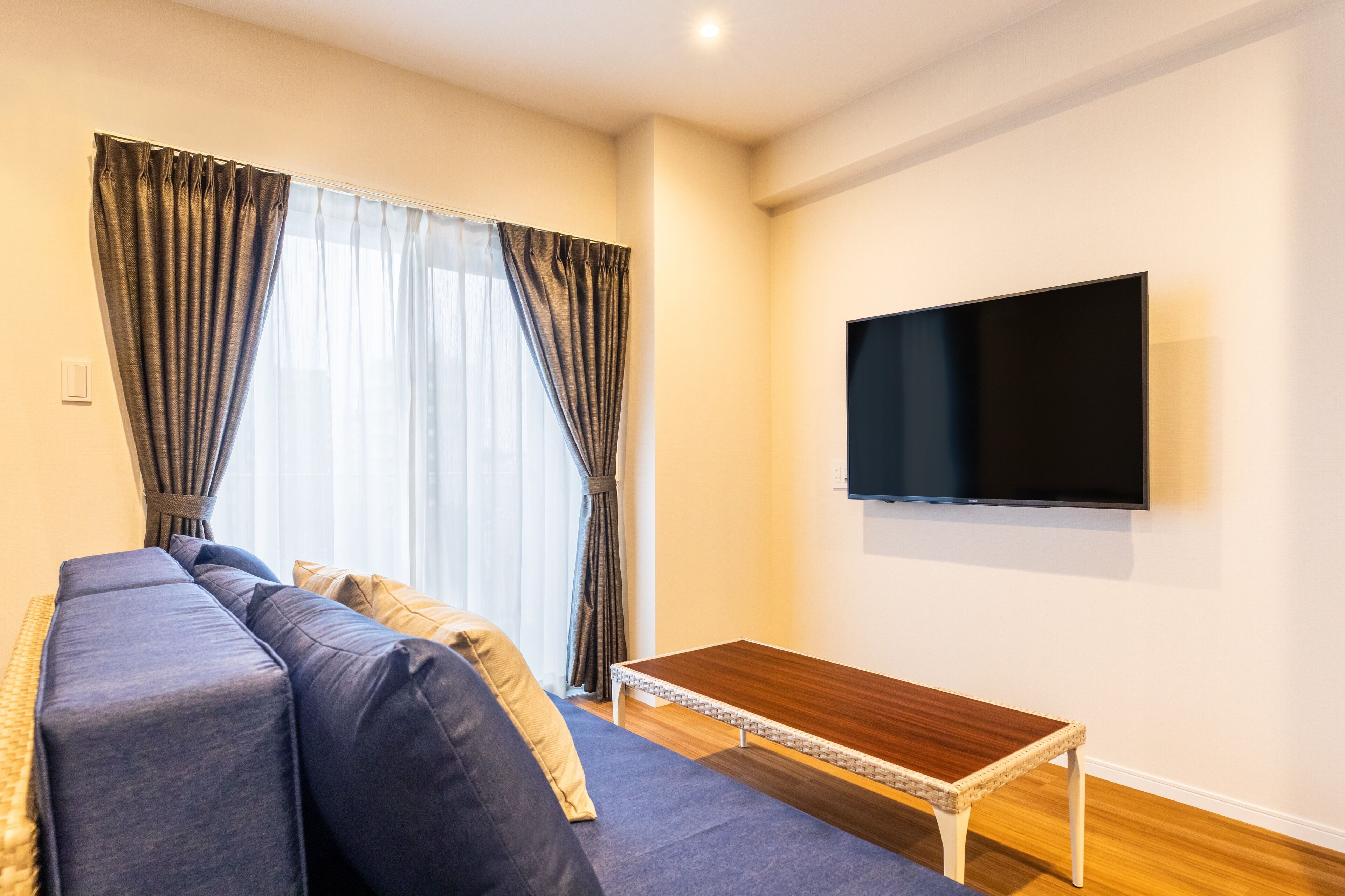 Una sala de estar moderna con un sofá, una mesa de centro y un televisor montado en la pared.