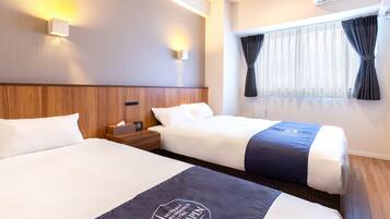 Een hotelkamer met twee bedden, een houten hoofdbord, nachtkastjes, een raam met gordijnen en een airconditioning.