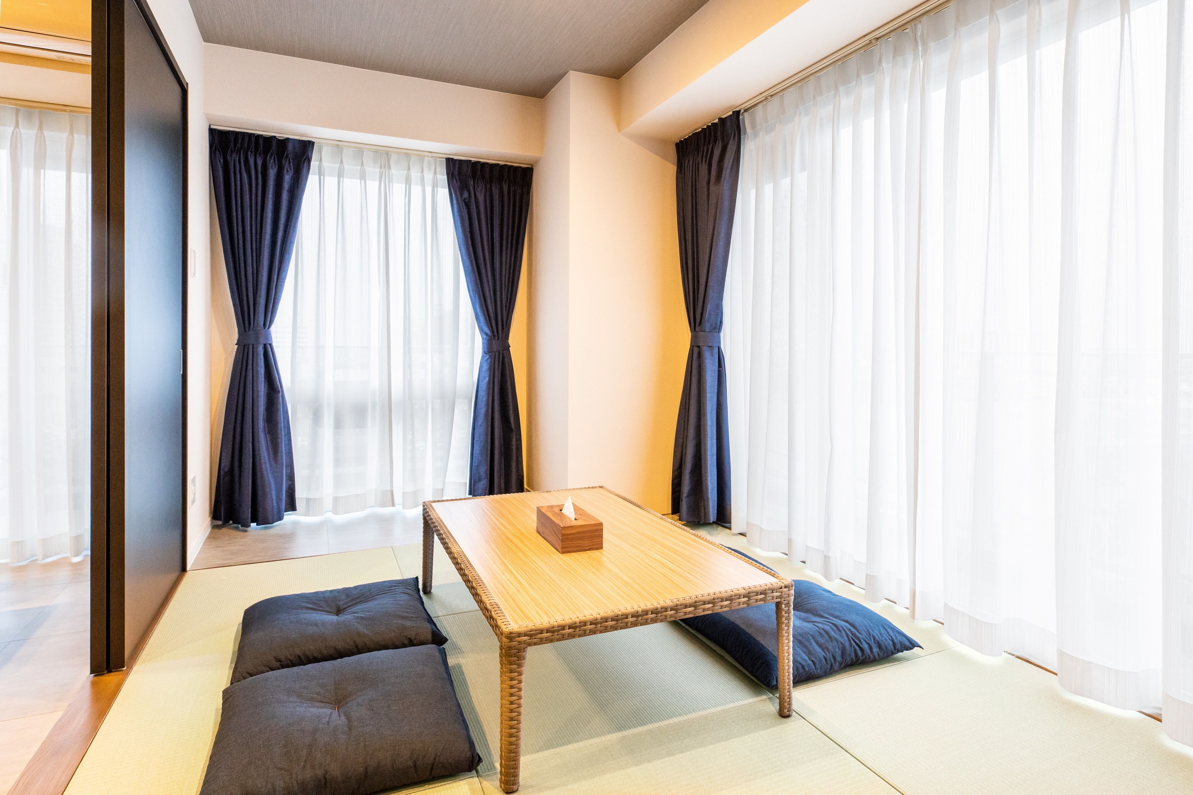 A room with tatami flooring, a low wooden table, and cushions.