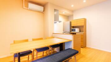 A compact kitchen with a wooden table, chairs, a bench, and a microwave.